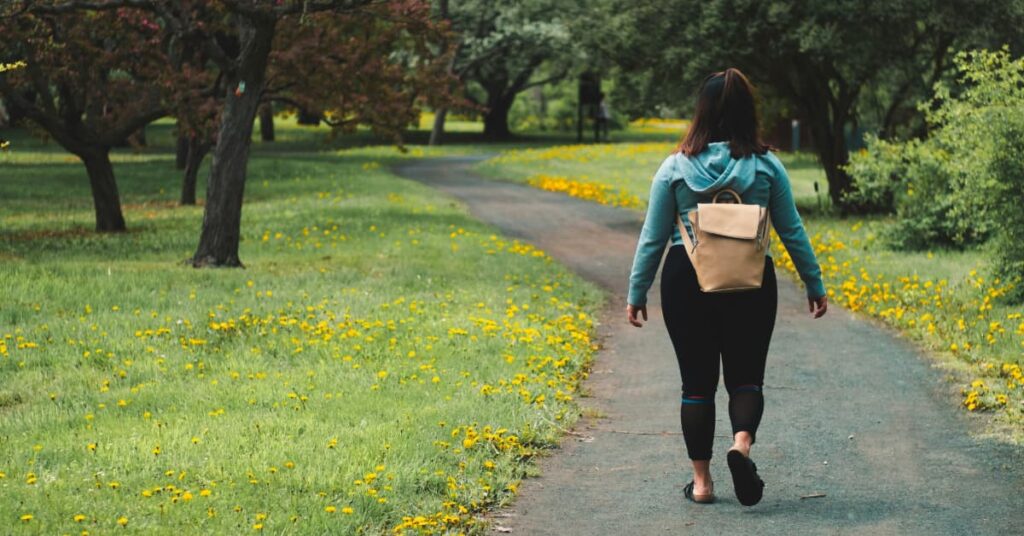 Woman walking on path surrounded by greenery